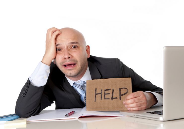 bald latin business man over worked holding a help sign